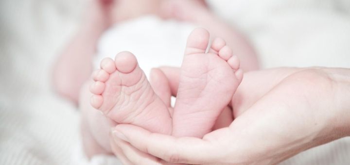 Baby feet held by adult hand- featured image for Rare unisex baby names ideas